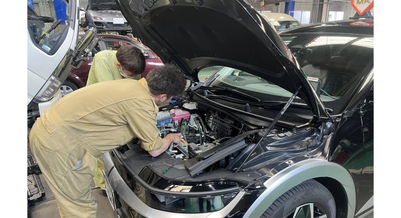 整備工場でエンジンルームを点検するメカニック